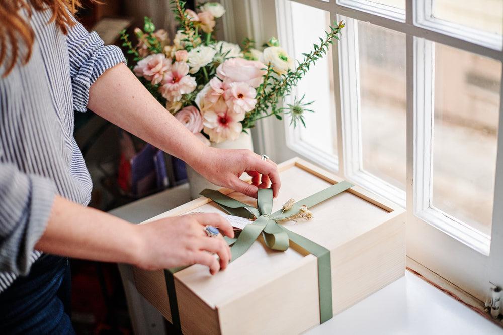 Santa Barbara Company Gift Box being tied up with green ribbon.